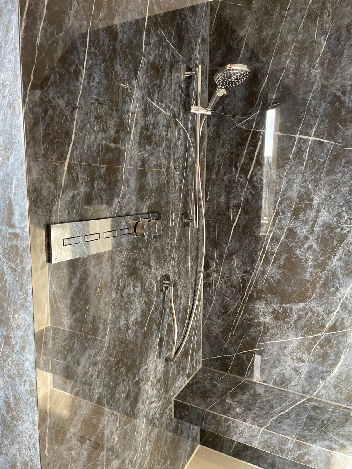Dusche in dunklem Marmor mit gemauerter Sitzbank