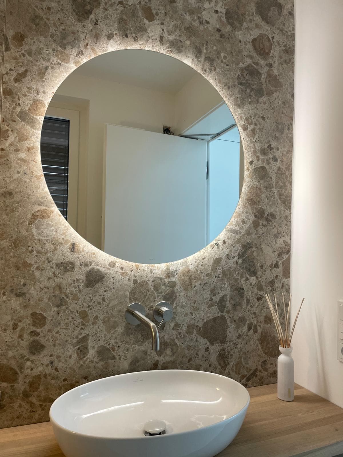 Runder beleuchteter Spiegel auf einer Wand in Terrazzo-Optik
