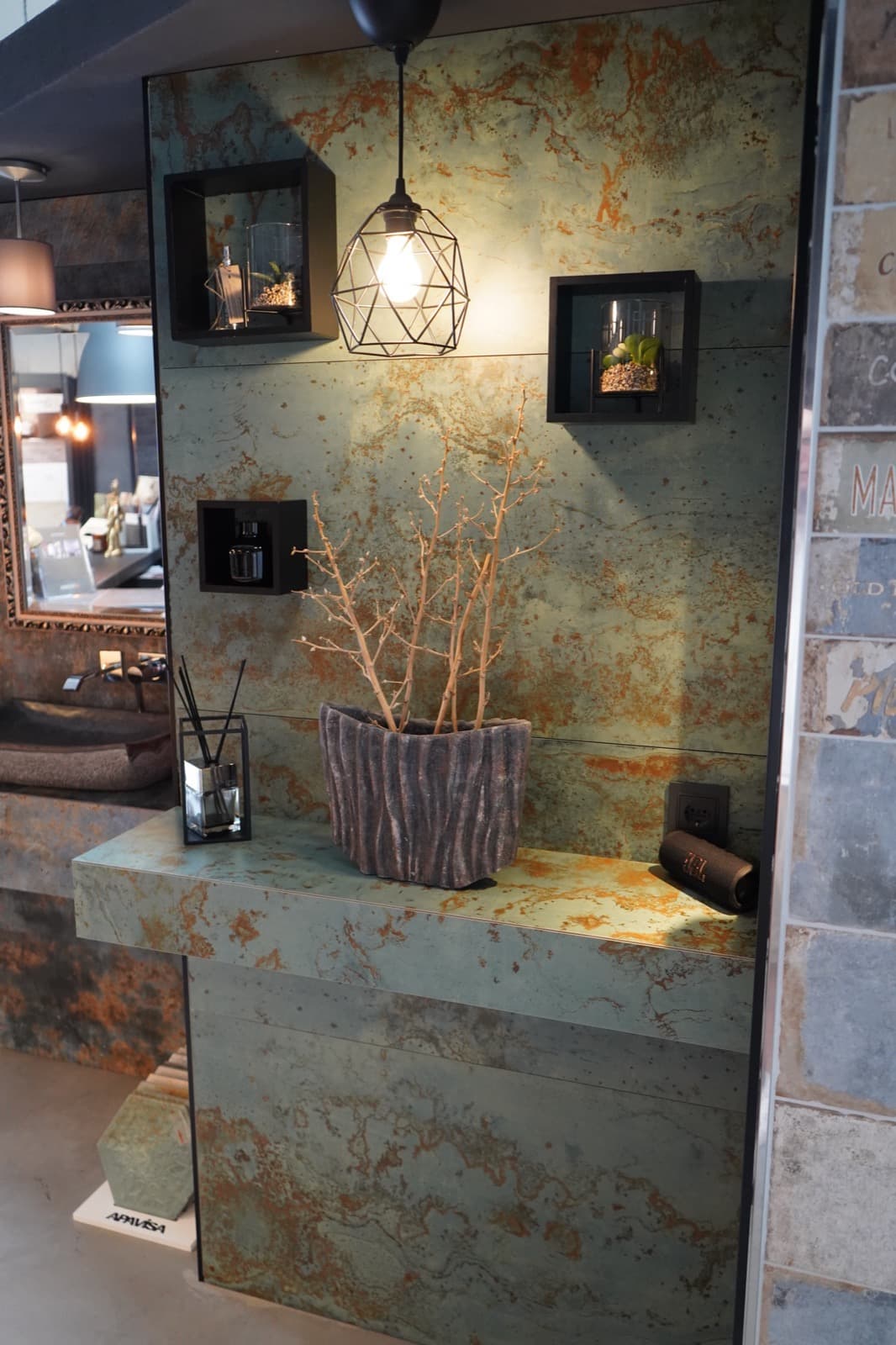 Ausstellungsvignette mit Patina-Fliese, Hängelampe, Deko-Nischen und Ast-Vase
