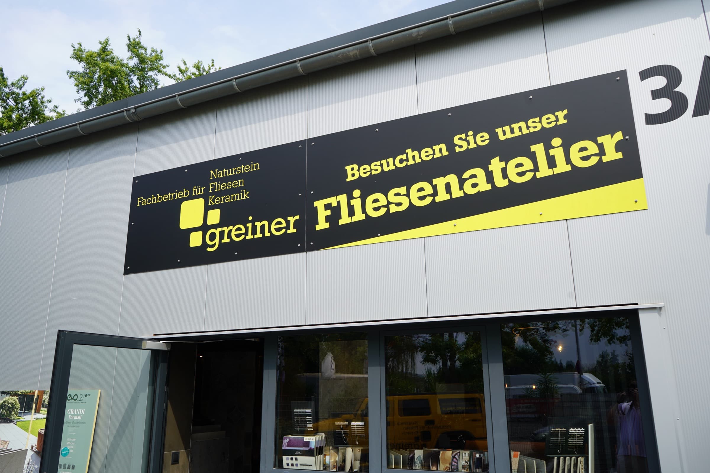 Das Firmenschild „Besuchen Sie unser Fliesenatelier“ über dem Eingang von Greiner Fliesen in Neustadt an der Weinstraße